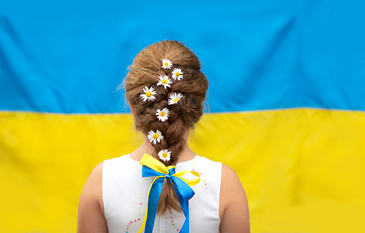 Una niña con margaritas en una trenza y una cinta amarilla y azul contra el fondo de la bandera de Ucrania. Día de la Independencia de Ucrania, Día de la Bandera, Día de la Constitución photo