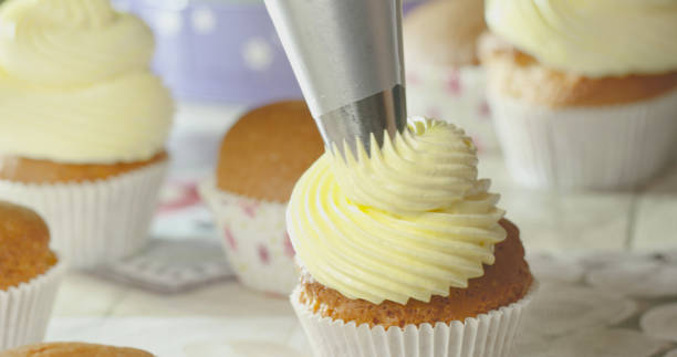 istock Squeezing Yellow Cream onto the Cupcake. 1329168728