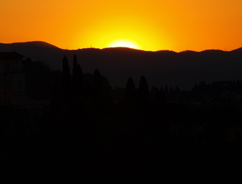 A glowing sunset behind the hills of Florence, Italy in mid-Spring. Two electricity pylons are visible on the top right horizon. This image was taken from the Piazzale Michelangelo. These are natural colours with no light or any other adjustments to this image.