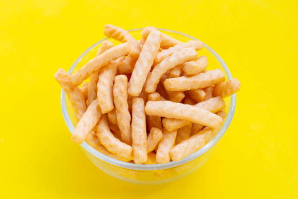 istock Prawn cracker sticks in glass bowl on yellow background. Shrimp crispy rice snack 1329168806