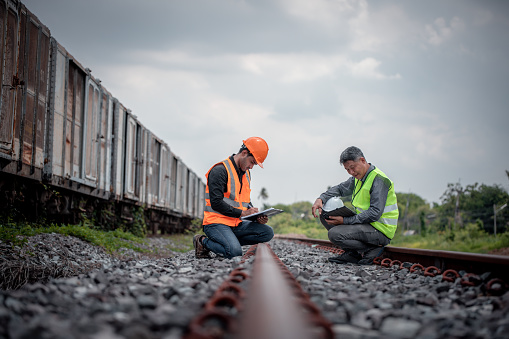 Engineer under discussion inspection and checking construction process railway switch and checking work on railroad station .Engineer wearing safety uniform and safety helmet in work.