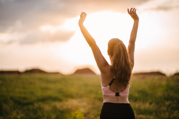 женщина, растягивающаяся на лугу - arms raised arms outstretched sky human arm стоковые фото и изображения