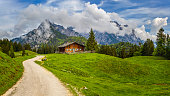 Idyllic landscape in the Alps with mountain chalet and meadows in springtime