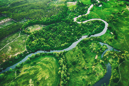 Aerial landscape of winding river in green field, top view of beautiful nature background from drone, seasonal summer landscape with copy space