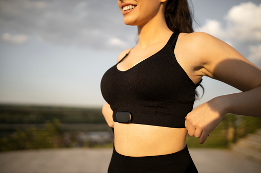 Close-up on a woman  putting on a fitness tracker to monitor her calories and heart rate - fitness goals concepts