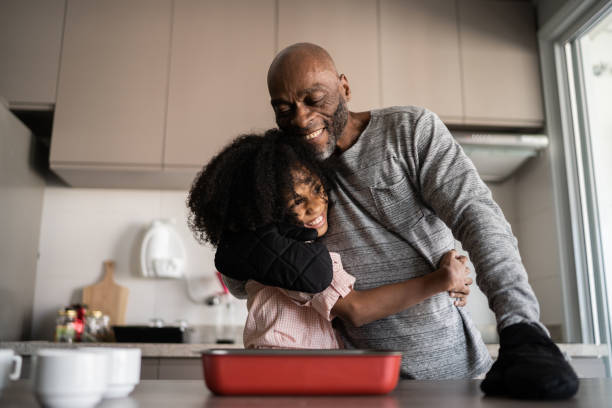 Father and daughter embracing and cooking together at home Father and daughter embracing and cooking together at home 55 59 years stock pictures, royalty-free photos & images