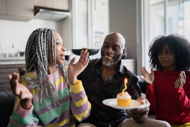 istock Daughters celebrating father's birthday with cupcake at home 1329182927
