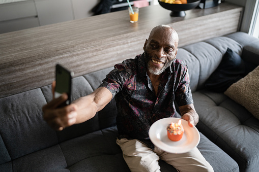 Mature man celebrating birthday doing a video call on smartphone at home