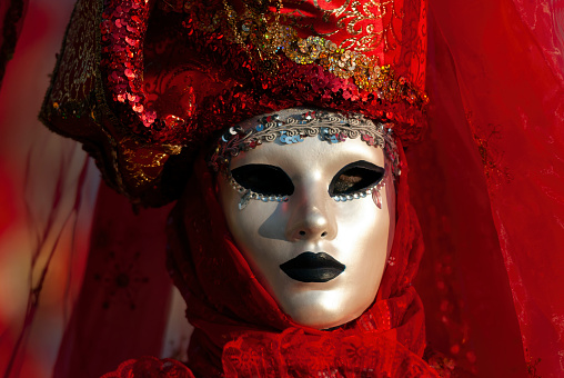 A golden carnival mask for festivals and performances with blue and red feathers around it