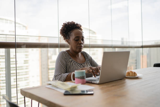 istock Mature woman using laptop working at home 1329183301
