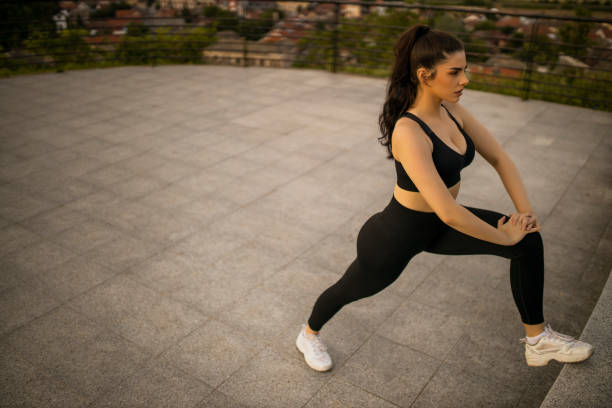 istock Happy young woman doing warm up exercise before jogging 1329186599