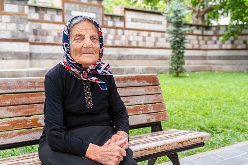 elderly woman sitting on bench and smiling looking at camera