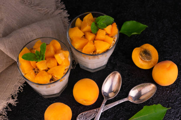 Apricot yogurt with muesli in a glass on a black background. View from above. stock photo
