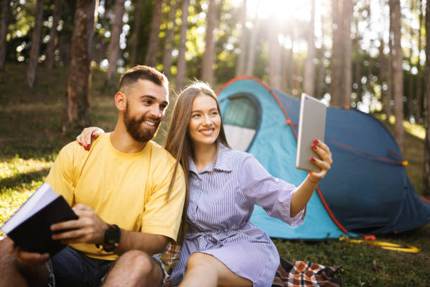 istock Happy couple having video call while camping in forest 1329190506