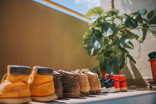 a row of shoes under hot sun at balcony beside house plant