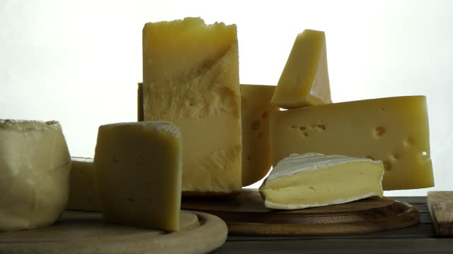 still life of different types of cheese on wooden plate, Italian Gorgonzola, parmigiano, French brie, cheeses on wooden cutting board slow rotation video