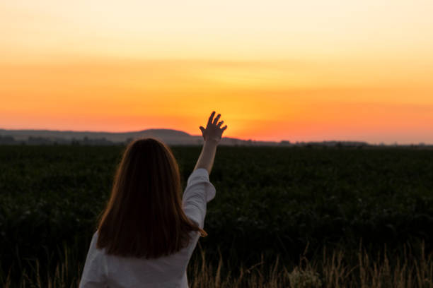 istock Young woman in field at sunset. 1329199763
