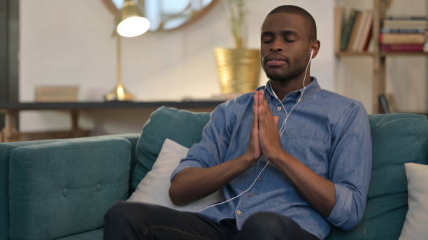 istock Spiritual Young African Man Meditating on Sofa 1329204589