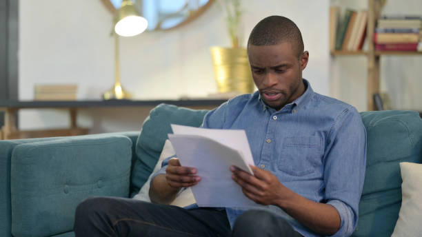 istock Young African Man Angry on Smartphone on Sofa 1329204630