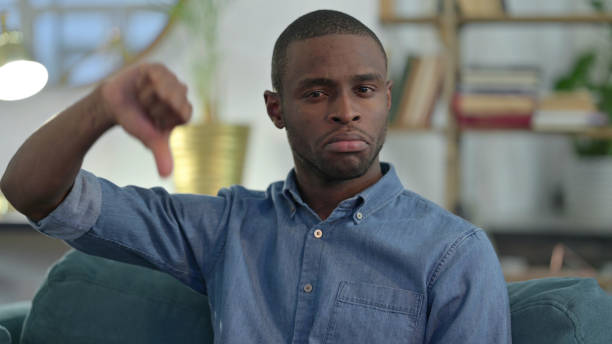 istock Young African Man with Thumbs Down at Home 1329204697