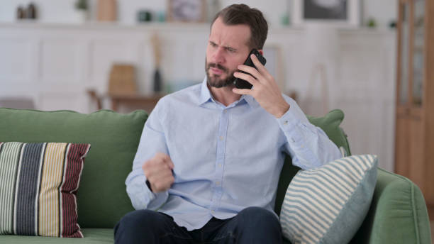 istock Angry Young Man Talking on Phone at Home 1329204705