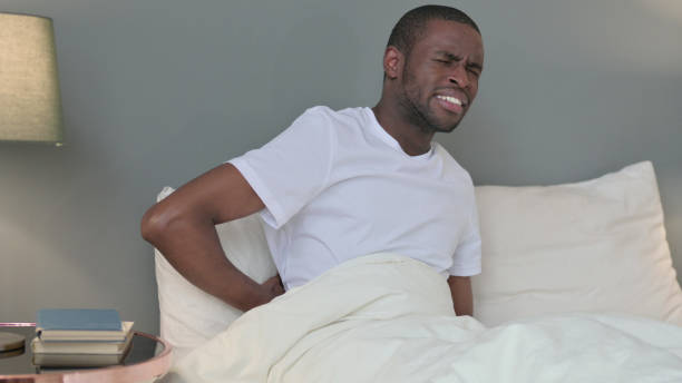 istock Exhausted Young African Man having Back Pain in Bed 1329204787
