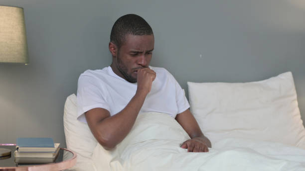 istock Sick Young African Man Coughing in Bed 1329204798