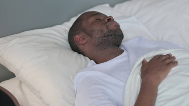 istock Young African Man Waking Up from Sleep in Bed 1329204846