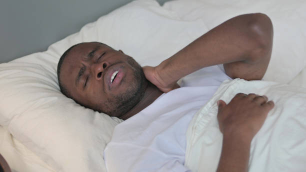 istock Exhausted Young African Man with Neck Pain in Bed 1329204854