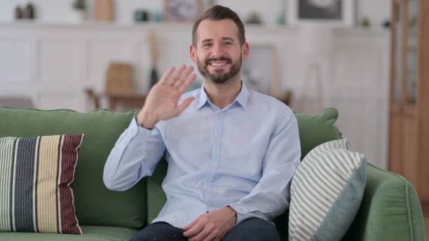 istock Hello by Welcoming Young Man Waving at Camera 1329204955