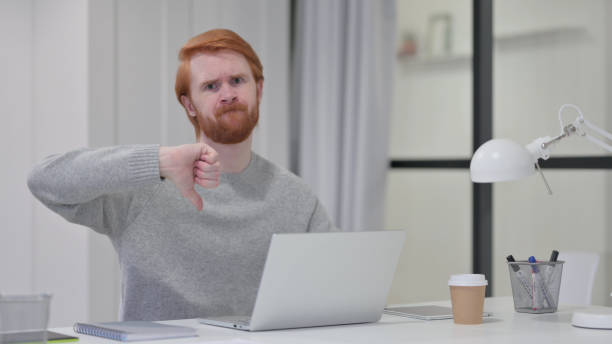 istock Thumbs Down by Young Beard Redhead Man with Laptop 1329205830