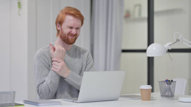 istock Beard Redhead Man having Wrist Pain while Typing on Laptop 1329205958