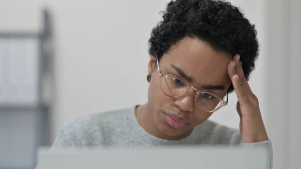 istock Close up of African Woman Thinking while using Laptop 1329206110