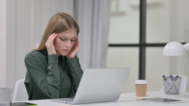 istock Young Woman with Headache Working on Laptop 1329207000