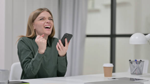 istock Successful Young Woman Celebrating on Smartphone 1329207108