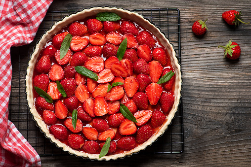 Raw fruit tart dessert sweet pie with fresh strawberry in making ready to bake on a wooden table top view