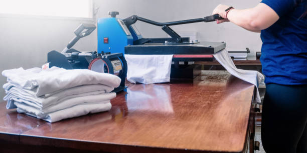 woman manipulating a sublimation machine ironing a shirt. advertising and screen printing concept. woman manipulating a sublimation machine ironing a shirt. advertising and screen printing concept. graphic print photos stock pictures, royalty-free photos & images