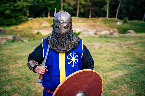 Sword in knight hand isolated on the gray background close up.