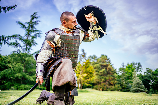 Medieval knight in full armor with a sword and a shield outdoor
