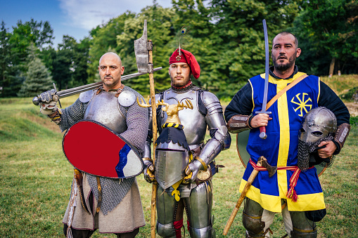 Three knights in armor outdoor with old weapon