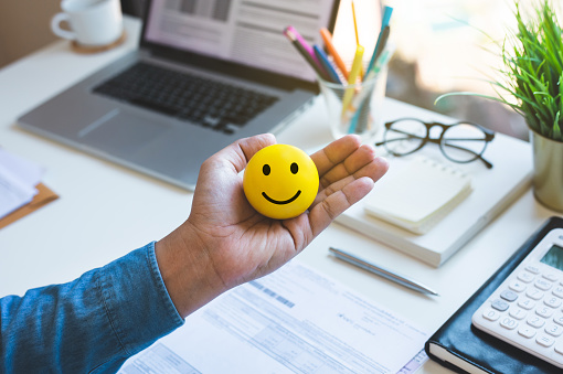 Bola de emoticono en la mano masculina en la mesa de trabajo.conceptos de vida feliz. photo