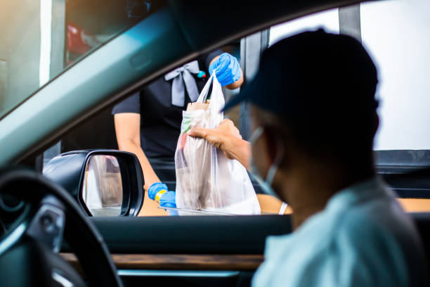 Selective focus to hand of staff wearing medical glove and mask  to handed a food to customer. Selective focus to hand of staff wearing medical glove and mask  to handed a food to customer. Drive thru and take away concept. drive through photos stock pictures, royalty-free photos & images