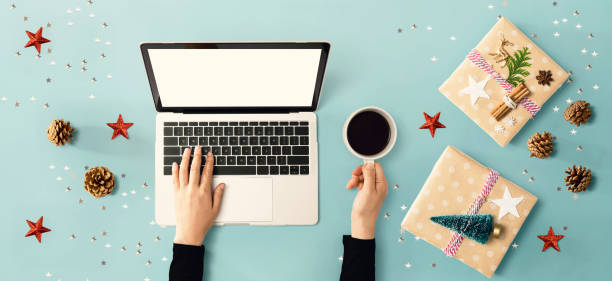 istock Christmas ornaments with person using a laptop computer 1329214037
