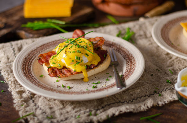 Delicious eggs benedict Organcic eggs benedict with bacon, cheddar cheese and herbs and hollandaise sauce hollandaise sauce stock pictures, royalty-free photos & images