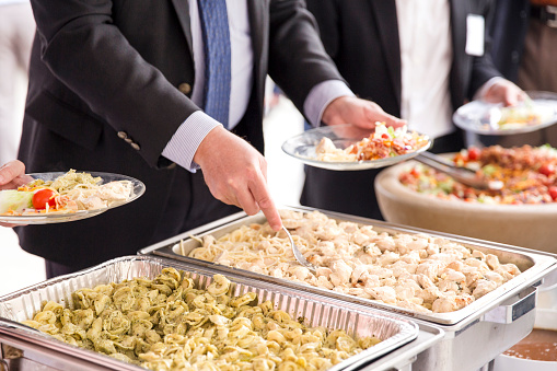 A businessman severing himself food at a catered corporate lunch.