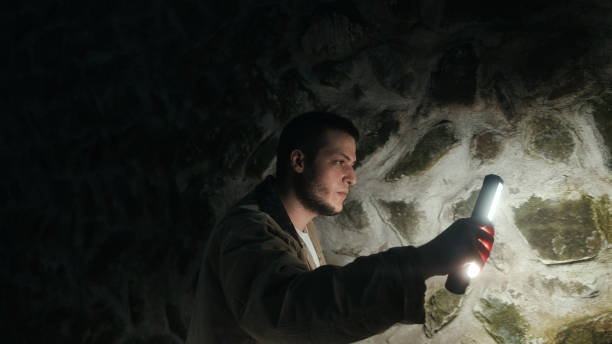 istock Young handsome tourist or archaeologist with a flashlight examining the walls inside a historic castle 1329227529