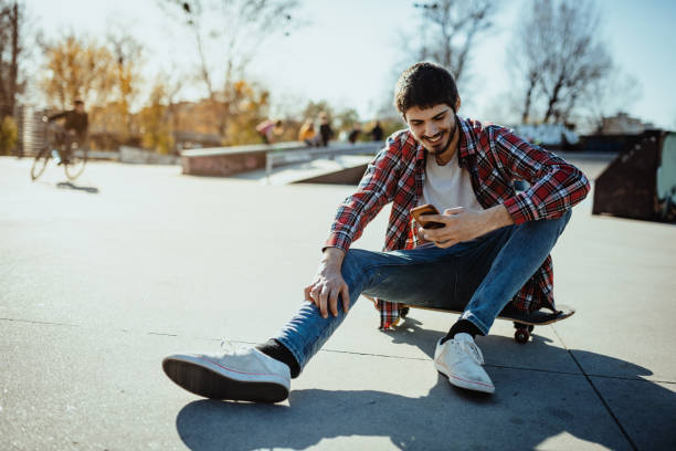 istock Young man skateboarding and using smart phone 1329245869