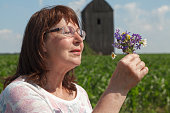 Elderly woman sniffing  bouquet of wild flowers close up
