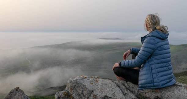 Female hiker relaxes on mountain ridge at sunrise