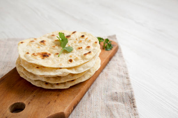 istock Homemade Roti Chapati Flatbread on a rustic wooden board on a white wooden surface, side view. Copy space. 1329247384